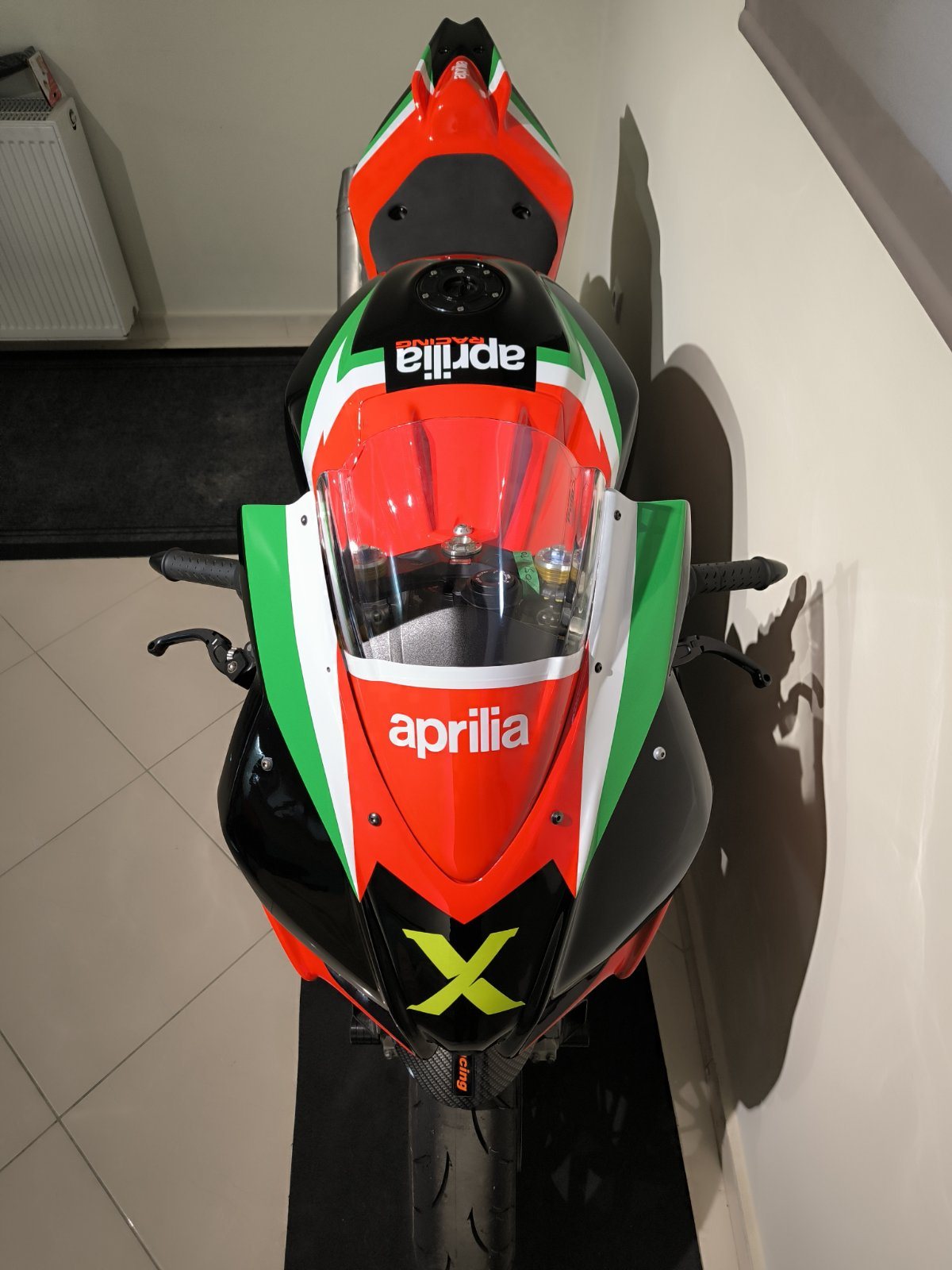Aprilia RSV4 seen head-on, showing the red, white and green fairing and the lime green X on the nose