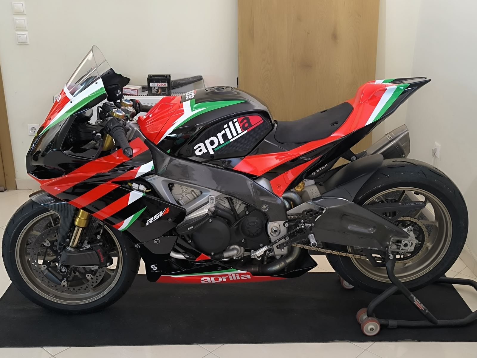 Side view of the repainted Aprilia RSV4 resting on paddock stands