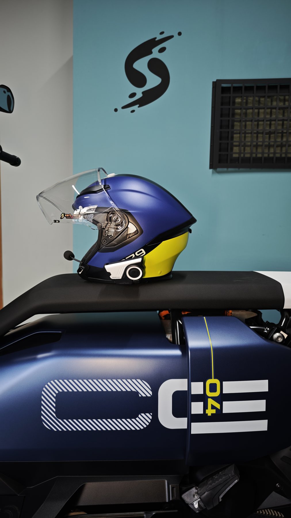 The helmet and the CE 04 side panel graphic seen together against the workshop wall