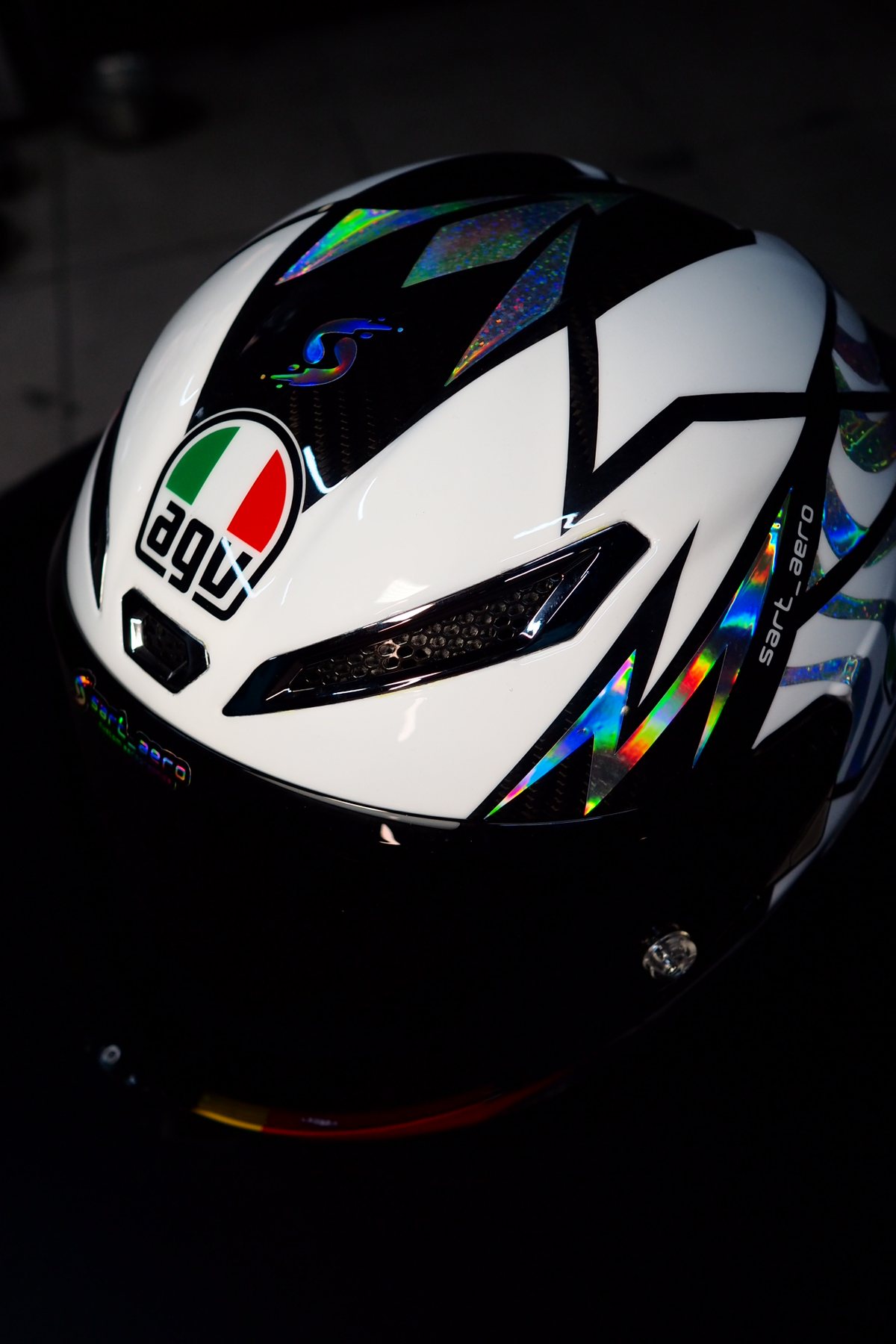 Front view against a dark background, showing the iridescent ribbons across the crown