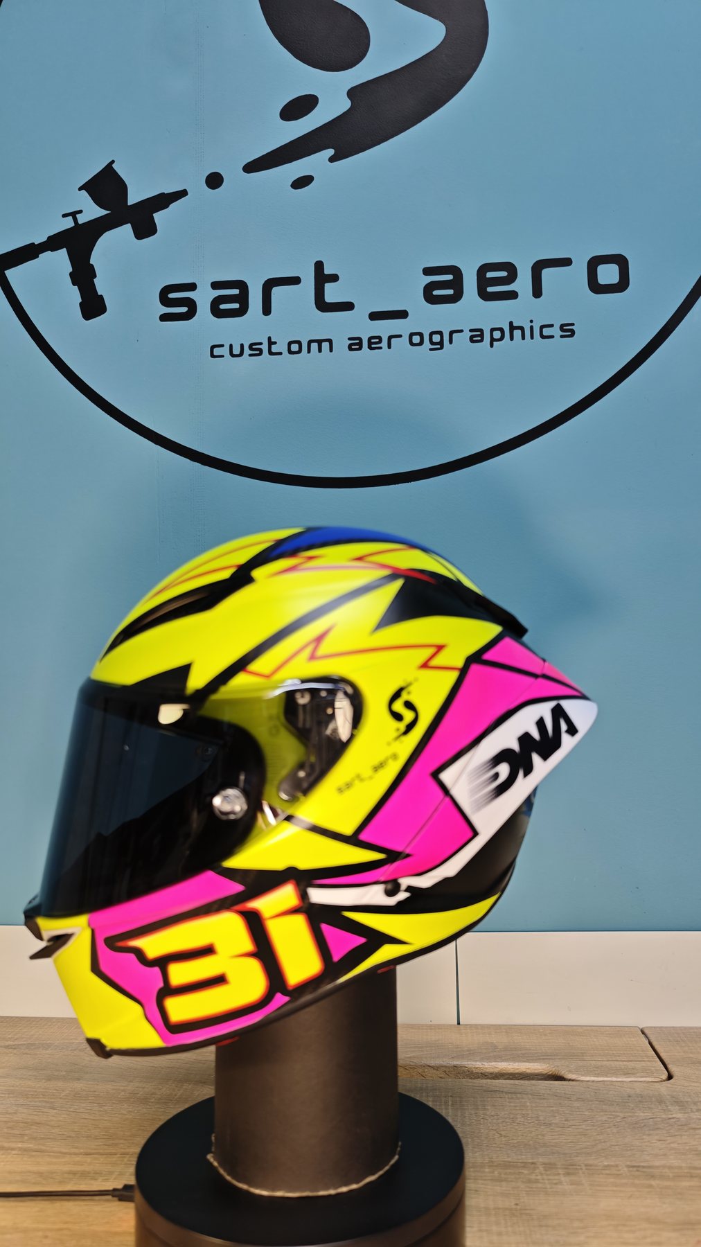 The helmet on its stand against the sart_aero workshop sign