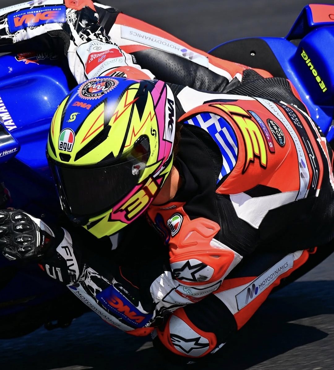 The rider at speed on track wearing the Dinos 31 helmet, knee down through a corner
