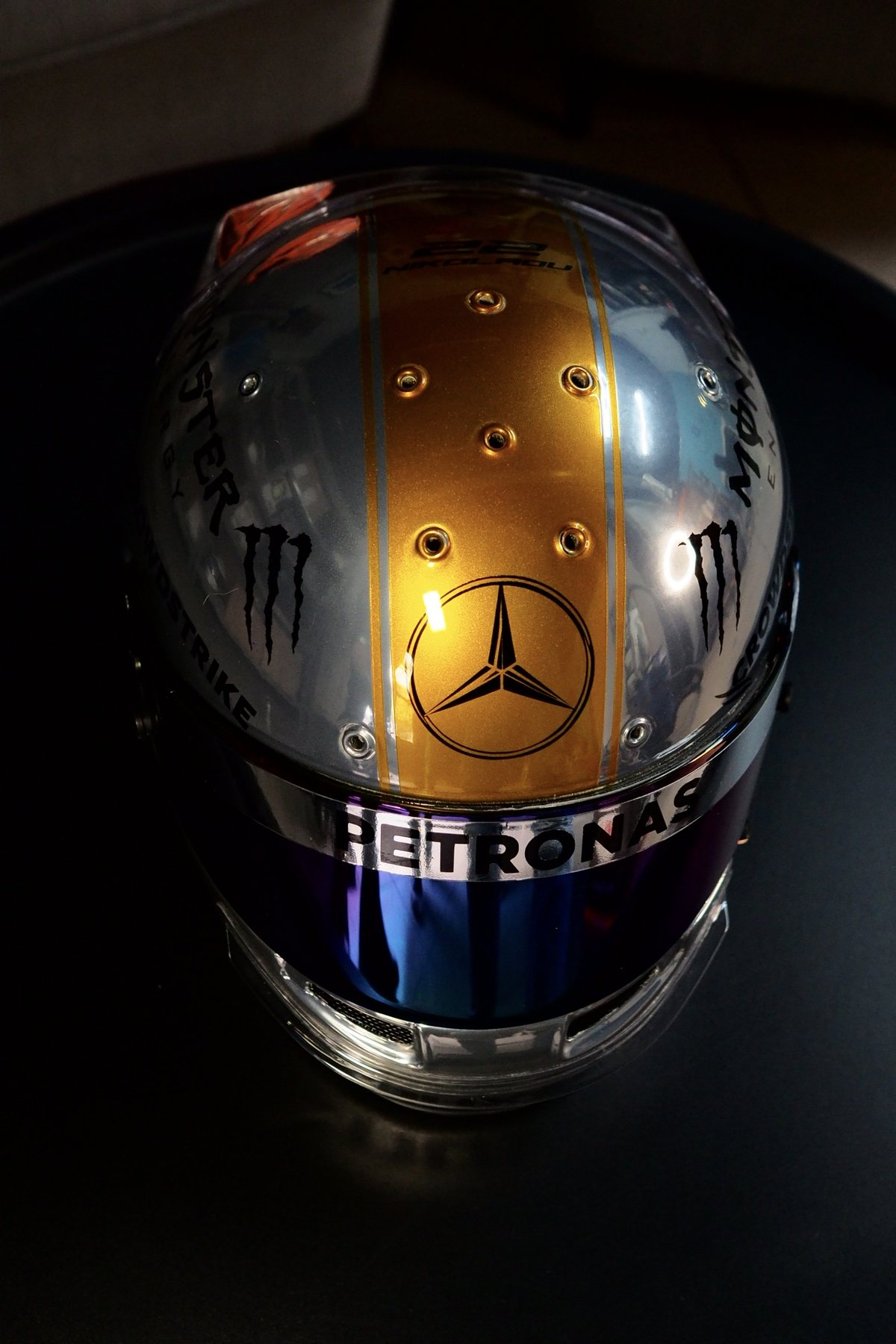 Front view of the Hamilton Replica tribute helmet, chrome-silver shell with a brushed-gold centre stripe
