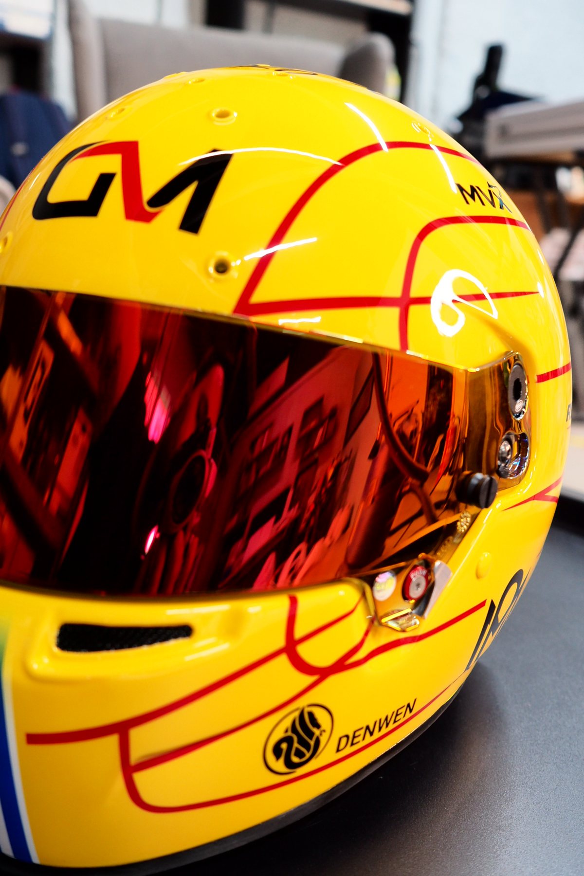 Front three-quarter of the Olympios kart helmet, yellow shell with red mirrored visor
