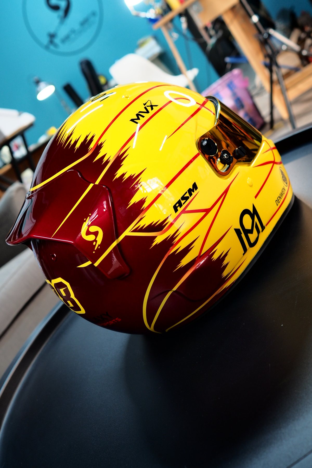 The helmet seen from above and behind, showing the burgundy rear and yellow flame boundary