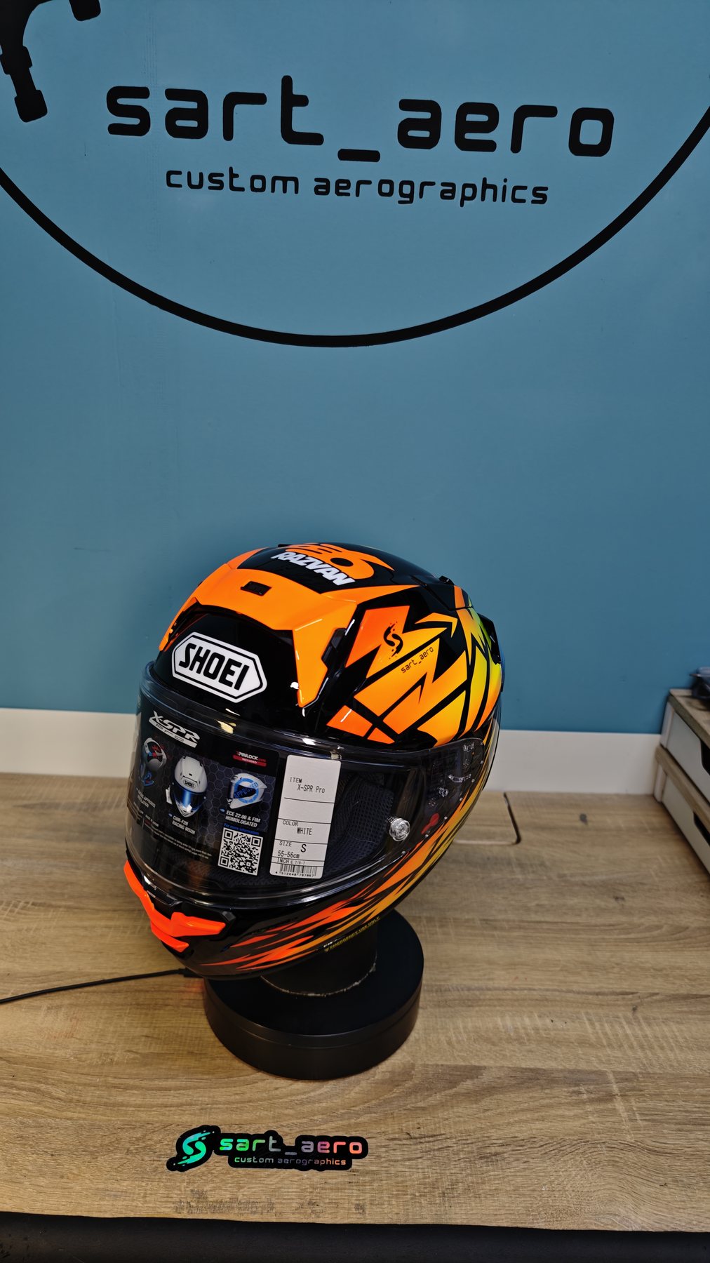 The Rsazvan 2026 helmet on its stand against the sart_aero workshop sign
