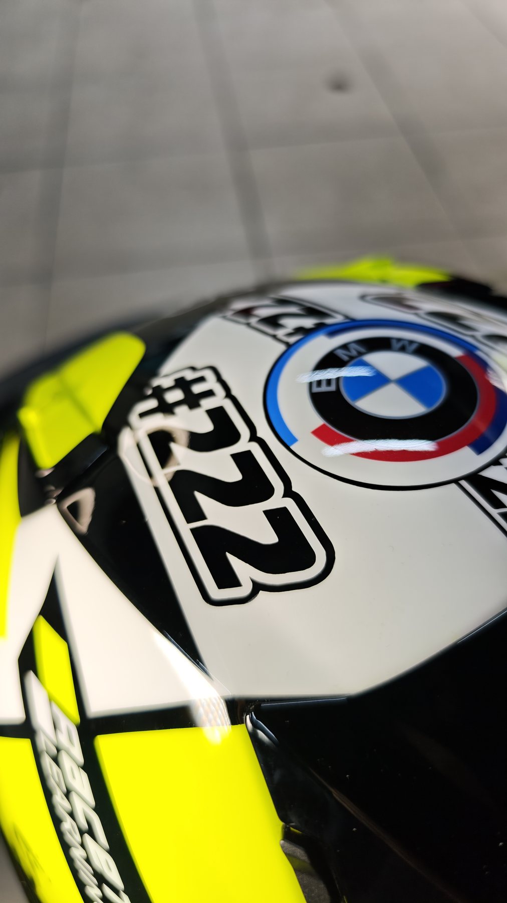 Detail of the Shai 222 helmet side panel, BMW roundel beside the outlined 222 on a white and fluorescent yellow ground