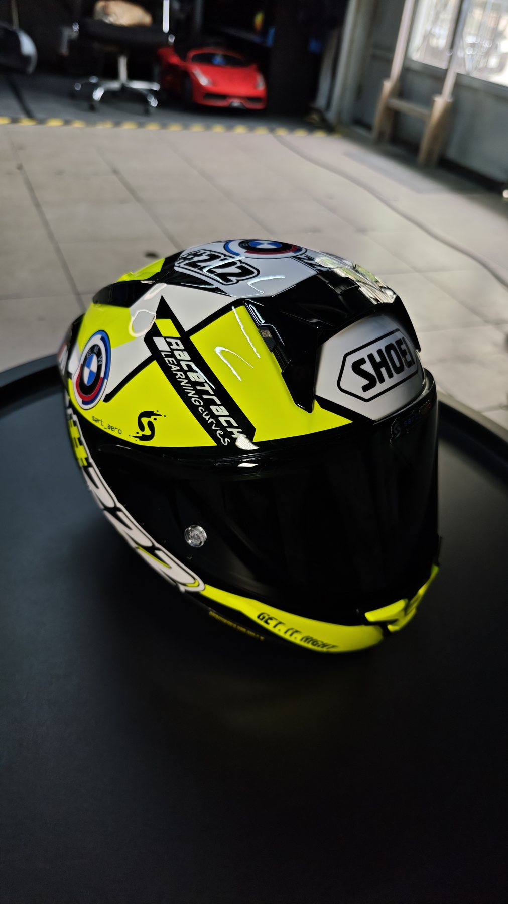 Rear three-quarter view of the Shai 222 helmet in the workshop, showing the Shoei spoiler and Racetrack Experience mark